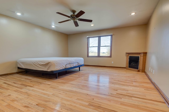 bedroom featuring light wood finished floors, a fireplace, and baseboards