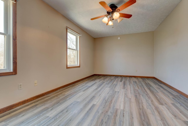 empty room featuring light wood-style flooring, ceiling fan, a textured ceiling, and baseboards