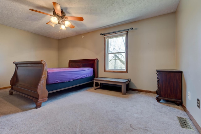 carpeted bedroom with baseboards, visible vents, ceiling fan, and a textured ceiling