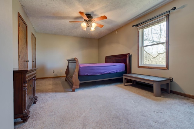 carpeted bedroom with a ceiling fan, baseboards, and a textured ceiling