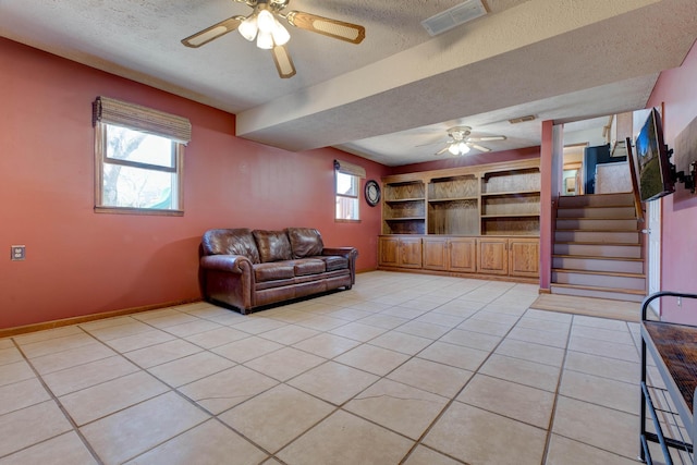 living room with stairway, visible vents, a textured ceiling, and light tile patterned floors