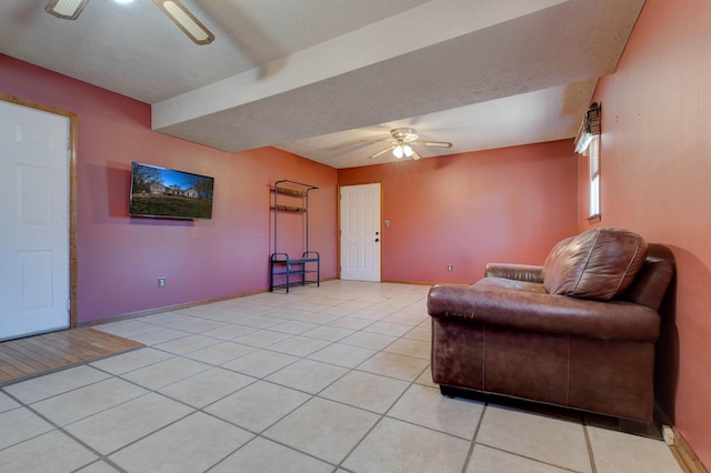 sitting room with light tile patterned floors, a textured ceiling, baseboards, and a ceiling fan