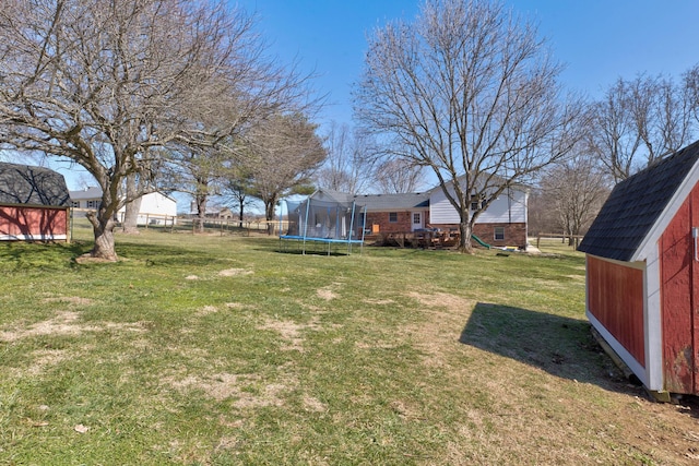 view of yard with a storage shed, a trampoline, fence, and an outdoor structure