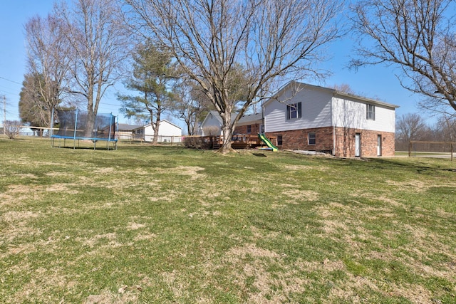 view of yard featuring a trampoline, fence, and a playground