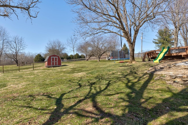 view of yard featuring a fenced backyard, a trampoline, a storage unit, an outdoor structure, and a playground