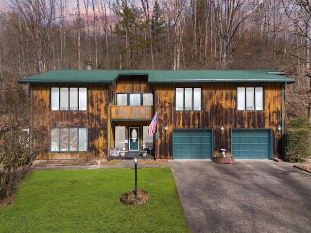 rustic home featuring an attached garage, metal roof, aphalt driveway, and a front lawn