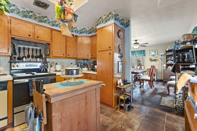 kitchen featuring ceiling fan, white dishwasher, a kitchen island, stainless steel range with electric cooktop, and decorative backsplash