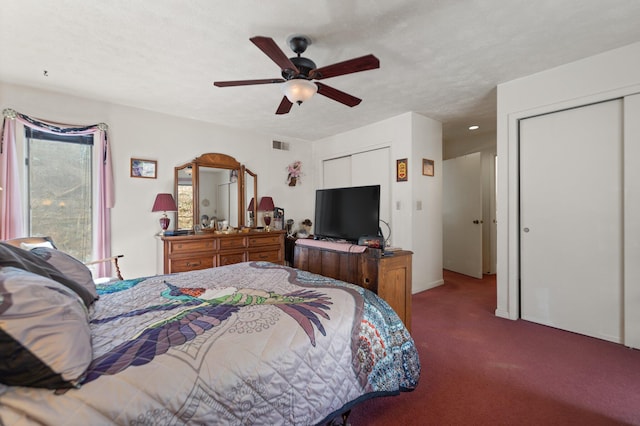 bedroom with carpet, two closets, visible vents, ceiling fan, and a textured ceiling