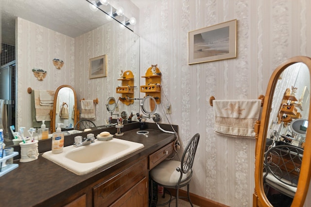 bathroom featuring vanity, baseboards, and wallpapered walls