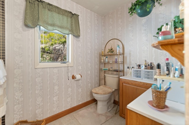 bathroom with toilet, wallpapered walls, tile patterned flooring, and baseboards