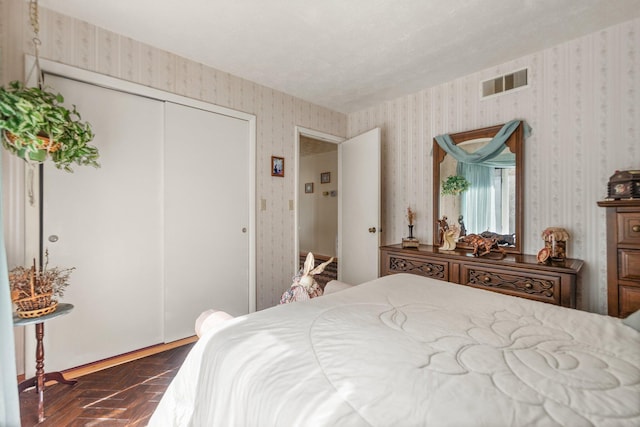 bedroom featuring a closet, visible vents, and wallpapered walls