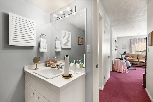 bathroom with a textured ceiling, connected bathroom, and vanity