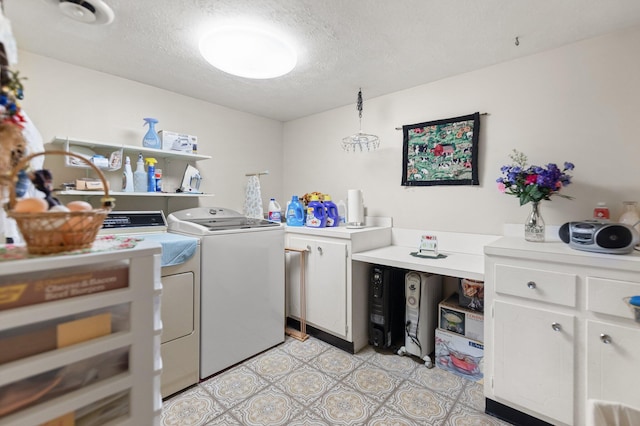 laundry area featuring a textured ceiling, light floors, washing machine and clothes dryer, and cabinet space