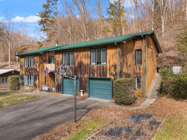 chalet / cabin with driveway, an attached garage, and metal roof