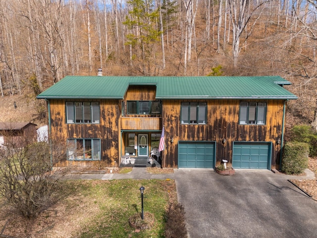 rustic home featuring a garage, metal roof, and driveway