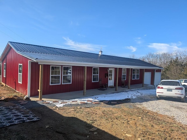 single story home with a garage, driveway, metal roof, and board and batten siding