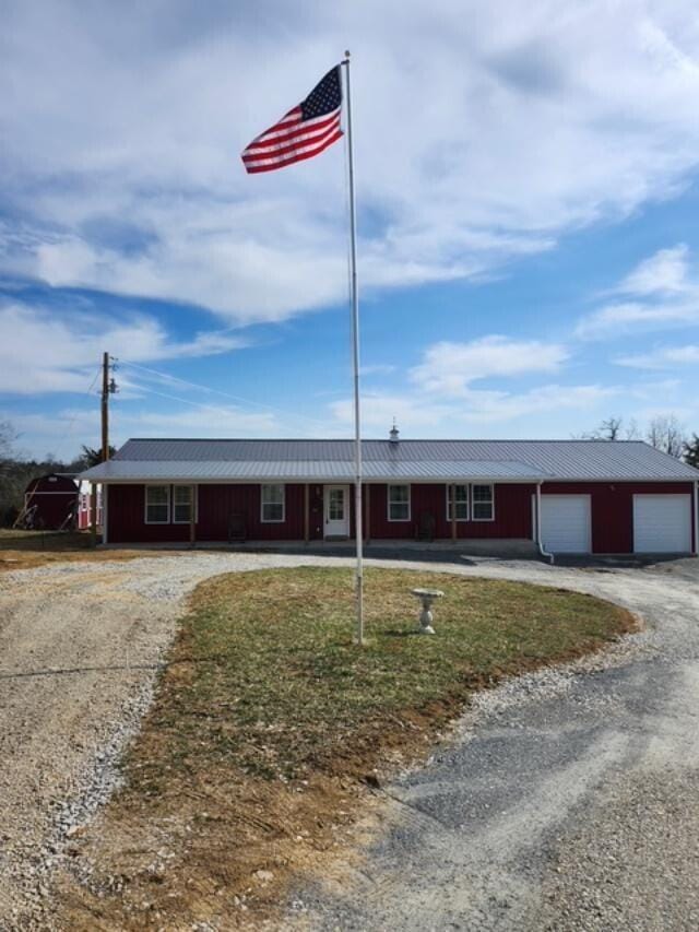 single story home featuring driveway and metal roof