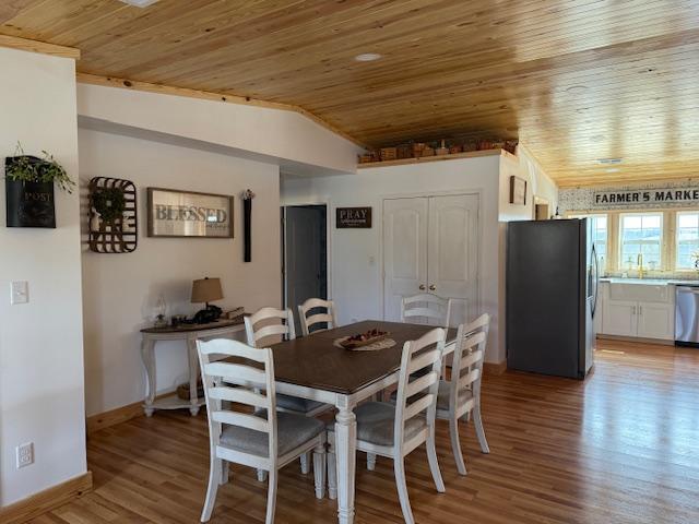 dining room with light wood-style flooring, wooden ceiling, baseboards, and lofted ceiling