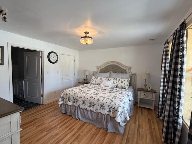 bedroom with visible vents, baseboards, and wood finished floors