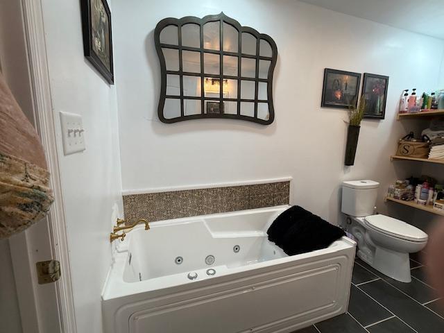 full bath featuring tile patterned floors, toilet, and a whirlpool tub