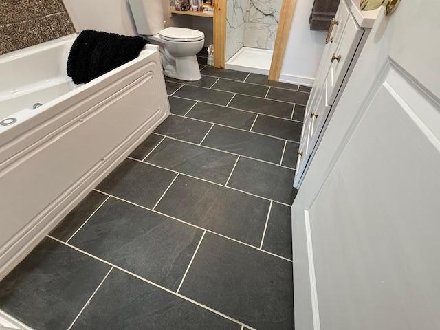 full bathroom featuring tile patterned floors, a washtub, toilet, and walk in shower