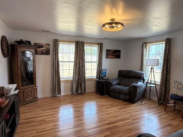 living area featuring visible vents, plenty of natural light, baseboards, and light wood-style flooring