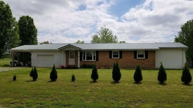 ranch-style house featuring brick siding, an attached garage, a front yard, metal roof, and driveway