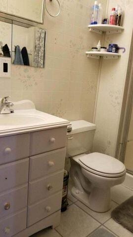 bathroom with toilet, tile patterned flooring, and vanity