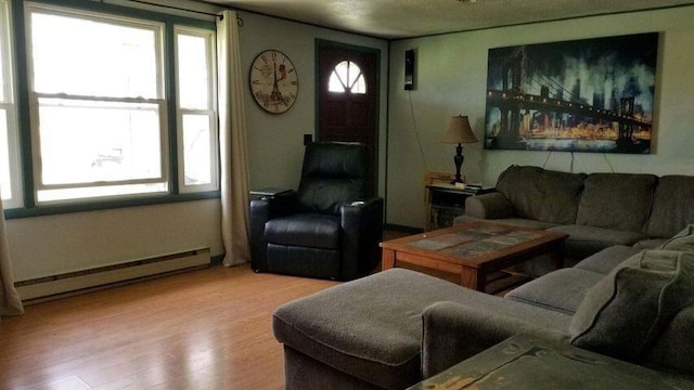 living room featuring a healthy amount of sunlight, a baseboard heating unit, and wood finished floors