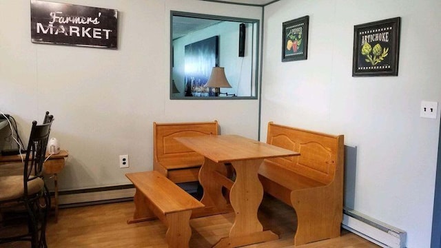 dining space with a baseboard heating unit and wood finished floors