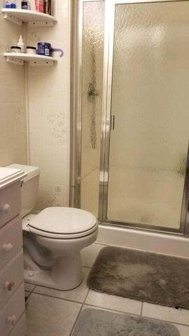 full bathroom with vanity, a shower stall, toilet, and tile patterned floors