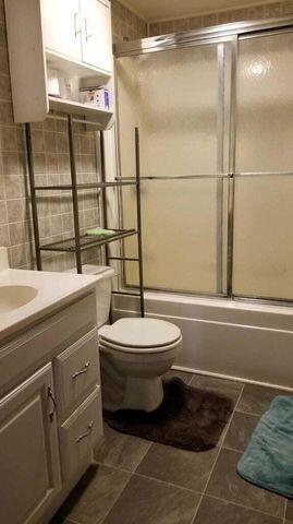 full bath with toilet, combined bath / shower with glass door, and vanity