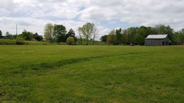 view of yard with a barn, a rural view, and an outdoor structure