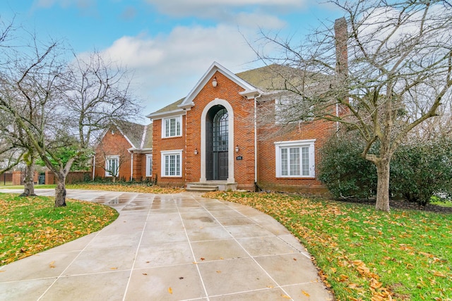 view of front facade featuring a front yard, concrete driveway, and brick siding