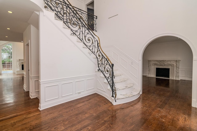 stairs featuring a premium fireplace, recessed lighting, wood finished floors, and a decorative wall