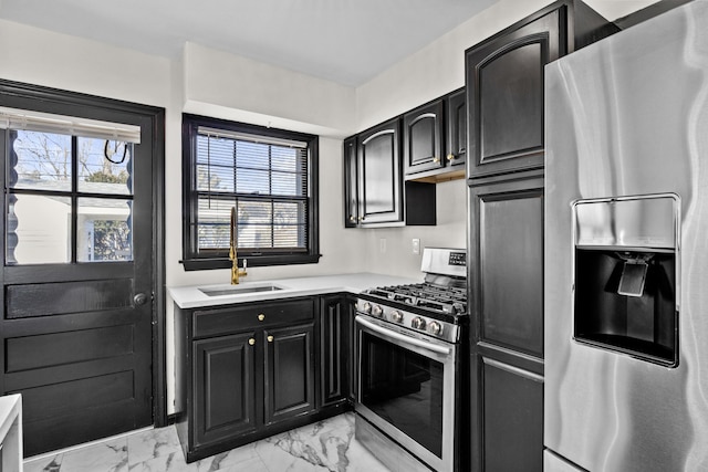 kitchen featuring marble finish floor, a wealth of natural light, appliances with stainless steel finishes, a sink, and dark cabinetry