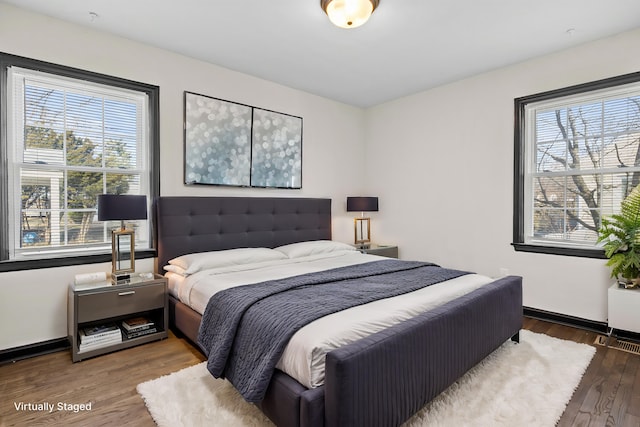 bedroom featuring multiple windows, wood finished floors, and baseboards
