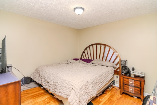 bedroom with light wood-style floors and a textured ceiling