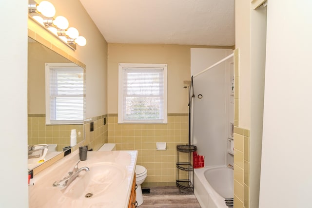 bathroom with tile walls, toilet, wainscoting, vanity, and wood finished floors