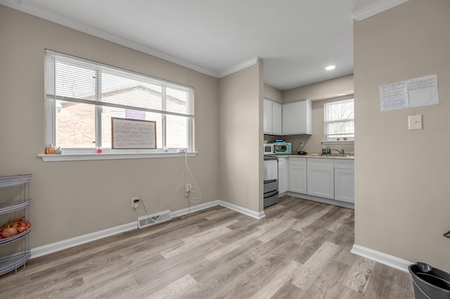 kitchen featuring crown molding, visible vents, stainless steel range with electric cooktop, light wood-type flooring, and baseboards