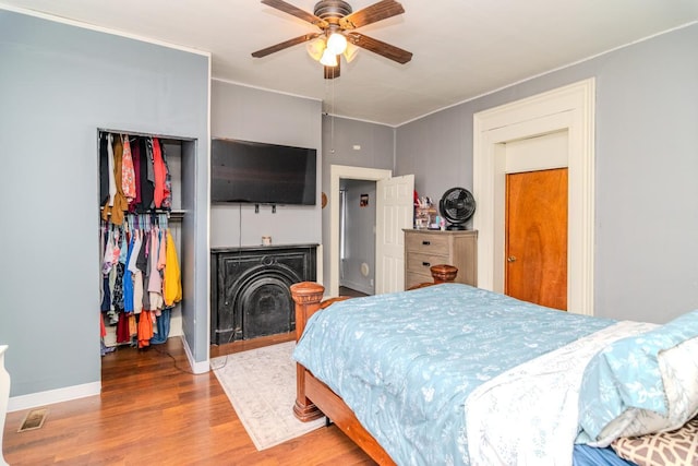 bedroom with baseboards, visible vents, ceiling fan, and wood finished floors