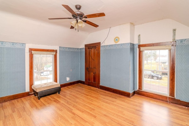 unfurnished room with lofted ceiling, wood finished floors, and wallpapered walls