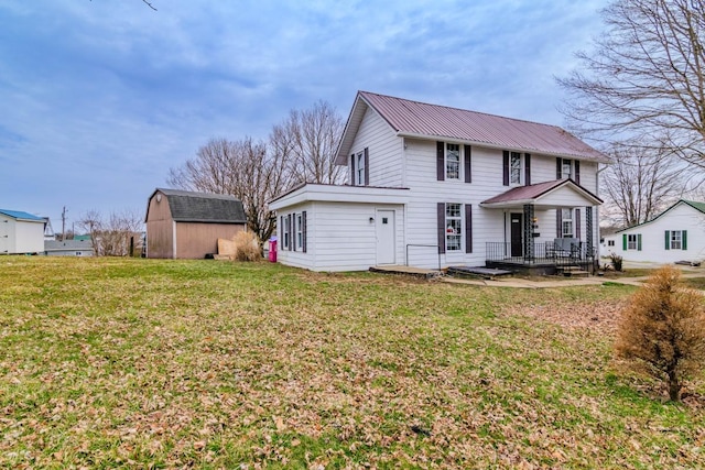 view of front of property featuring an outbuilding, metal roof, and a front lawn