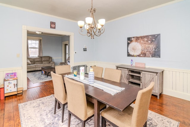 dining room with wood-type flooring, crown molding, and wainscoting