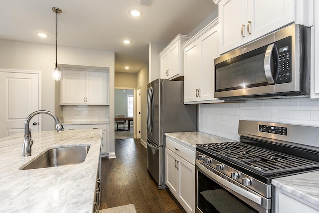 kitchen featuring decorative light fixtures, appliances with stainless steel finishes, dark wood-type flooring, white cabinets, and a sink