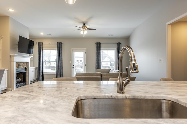 kitchen with a wealth of natural light, open floor plan, a fireplace, and a sink