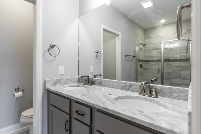 bathroom with double vanity, a sink, toilet, and a shower stall