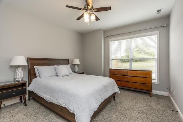 carpeted bedroom with a ceiling fan, visible vents, and baseboards