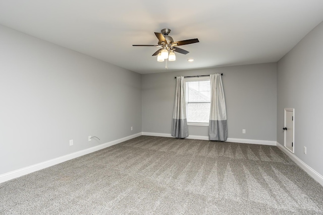 spare room with ceiling fan, baseboards, and dark colored carpet