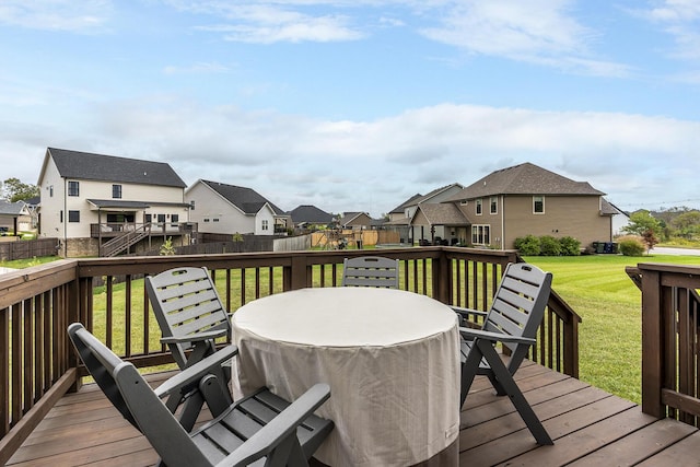 wooden terrace featuring a residential view, fence, outdoor dining area, and a yard